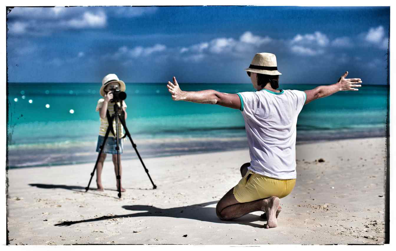 A young woman taking a photograph of a man at the beach.