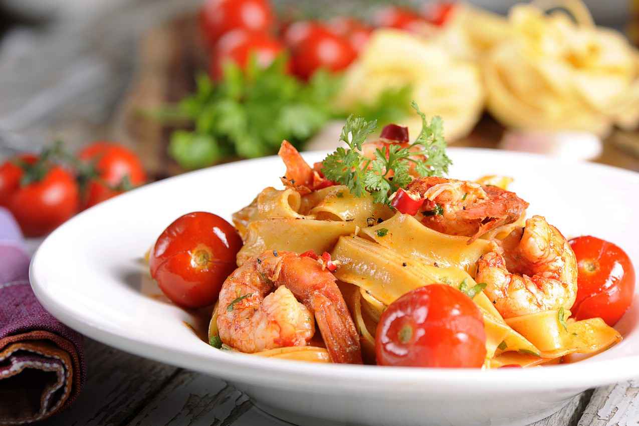 Seafood pasta served with sliced cherry tomatoes.