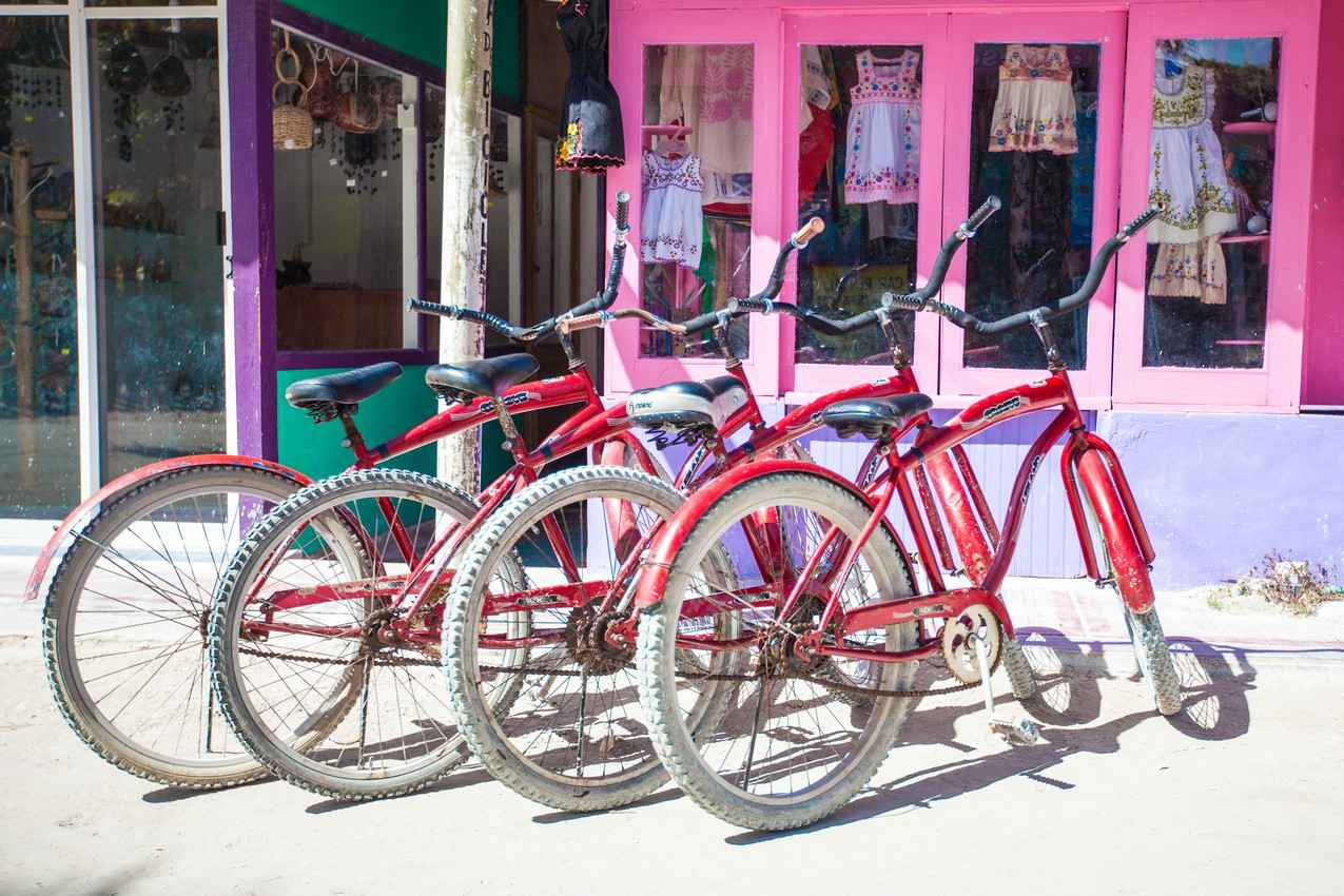 Four bikes resting on a sidewalk in Playa Del Carmen.