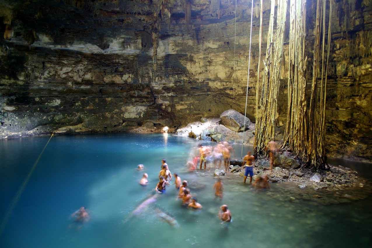 A group of people swimming and playing inside a cenote.