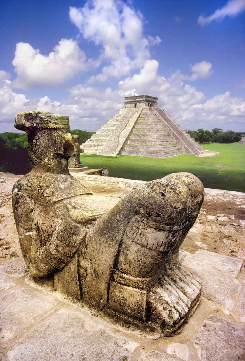 A statue of a Mayan king near one of the large pyramids.
