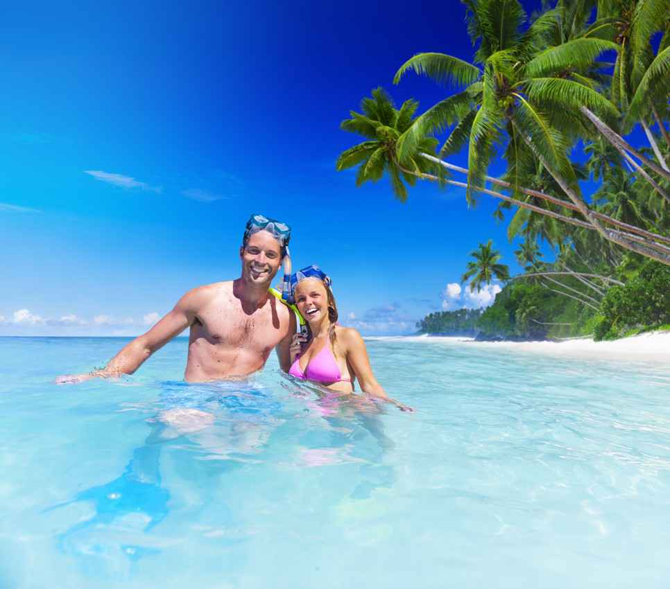A man and a woman snorkeling in shallow tropical waters.