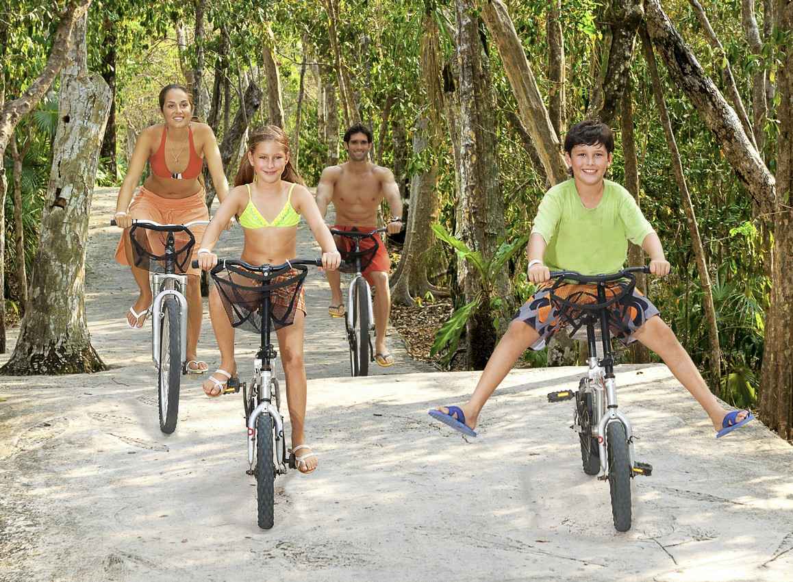 A family of four riding bikes on a jungle road tour.