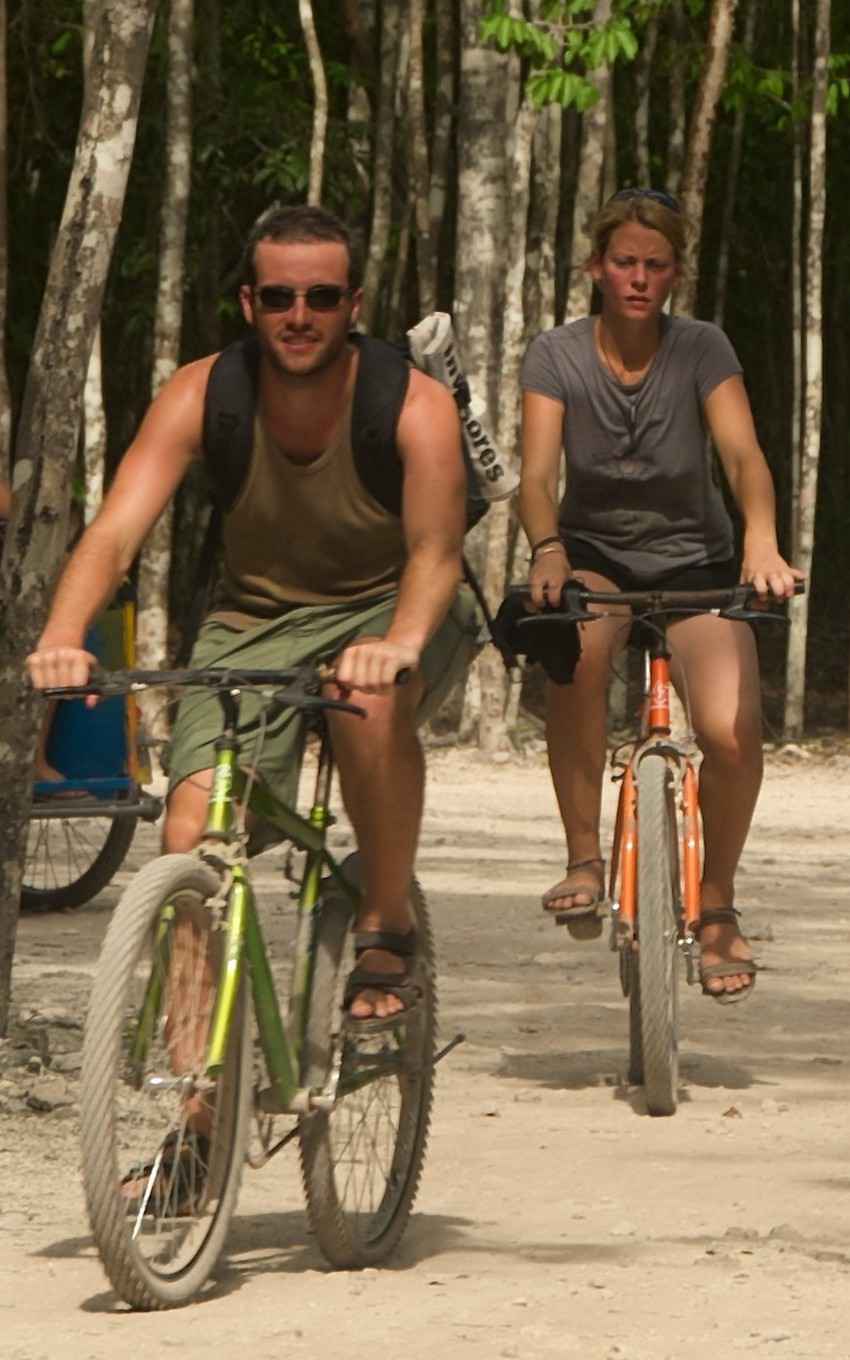 A man and a woman riding bikes on a jungle trail.