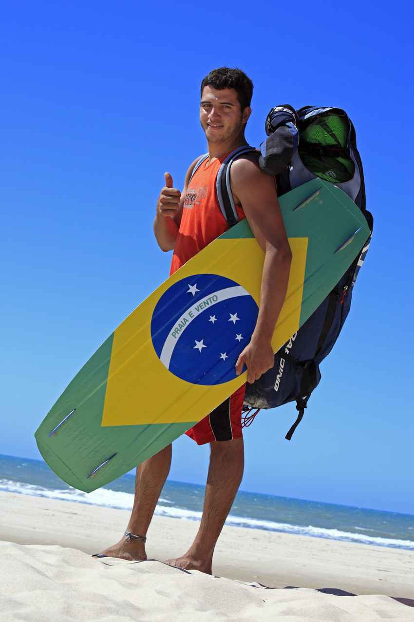 A Brazilian man holding a kite board with a Brazilian flag.