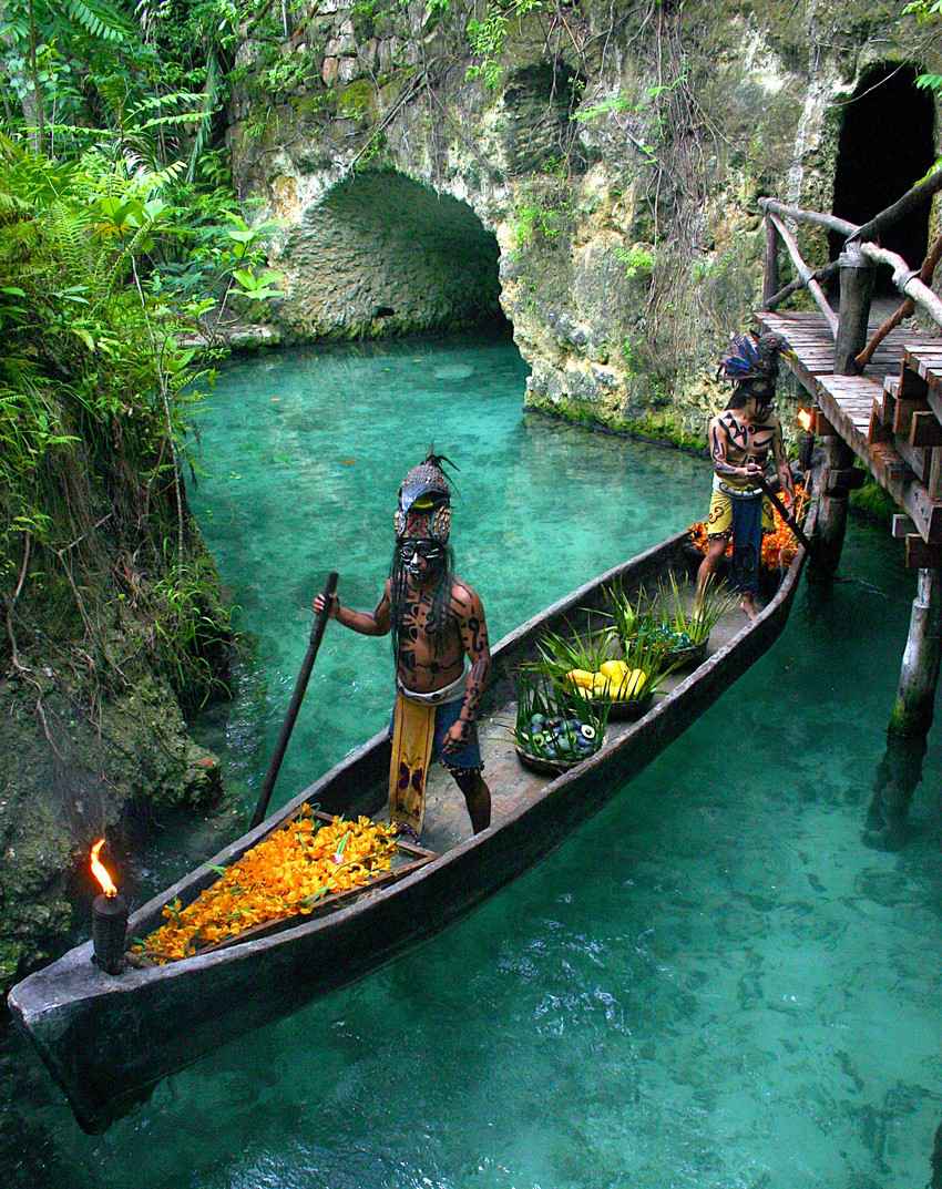 Several Mayan warriors riding a canoe on the hidden River near Playa Del Carmen.