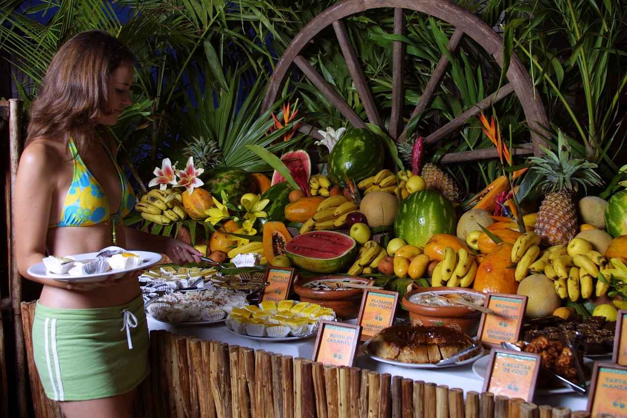 A variety of fresh fruits and desserts at a buffet.