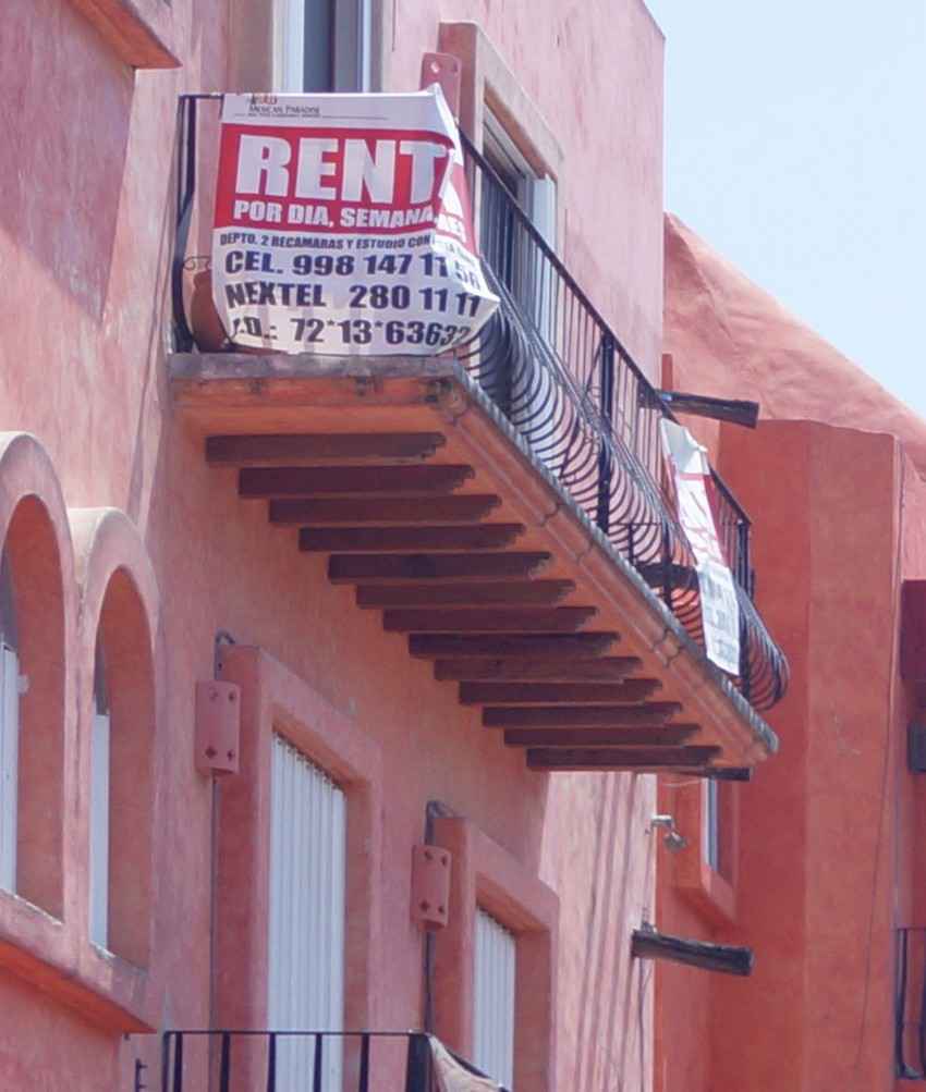 An apartment in downtown Playa Del Carmen with a FOR RENT sign hanging from the balcony.