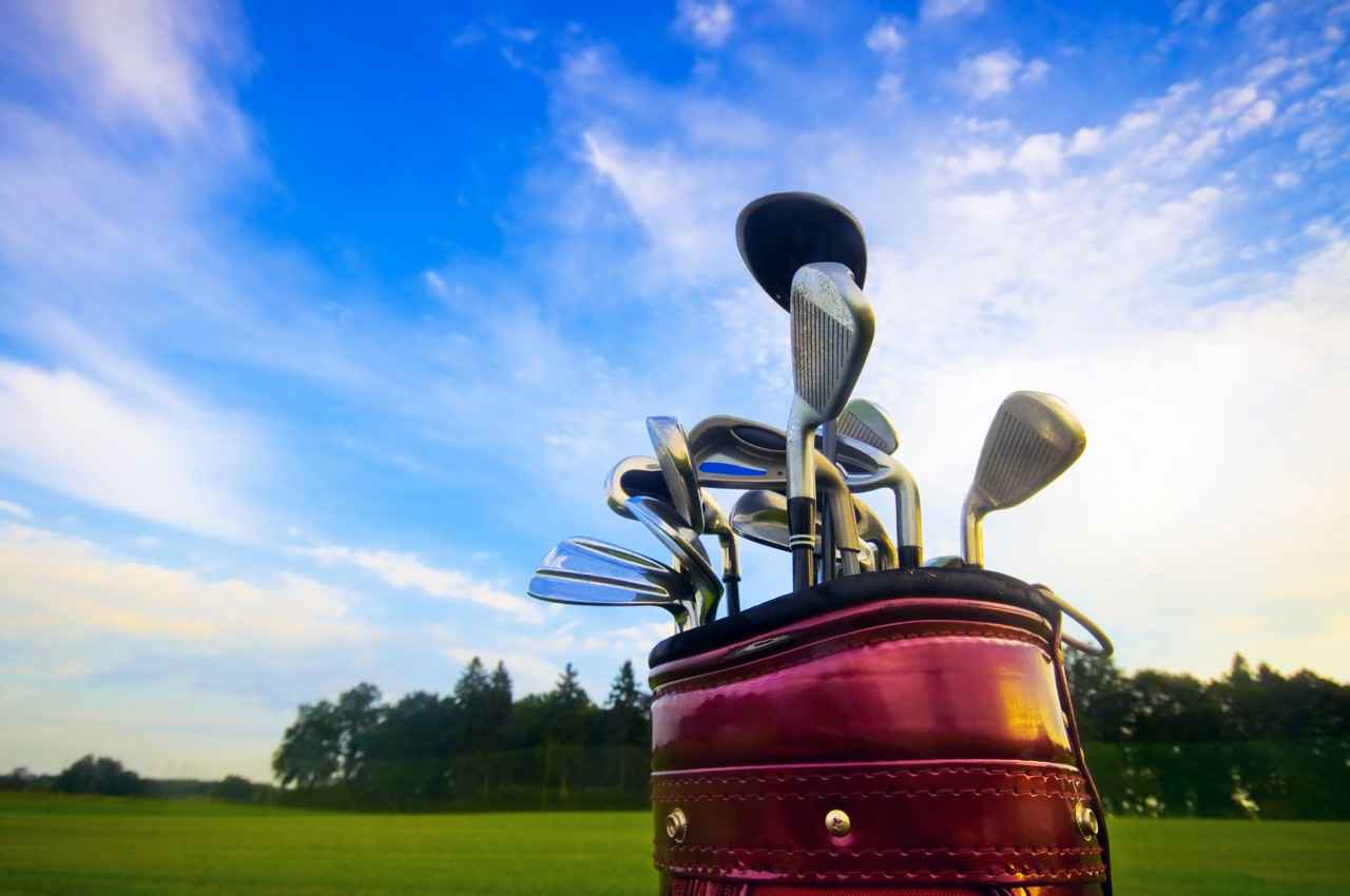 A set of golf clubs and a bag on a course.