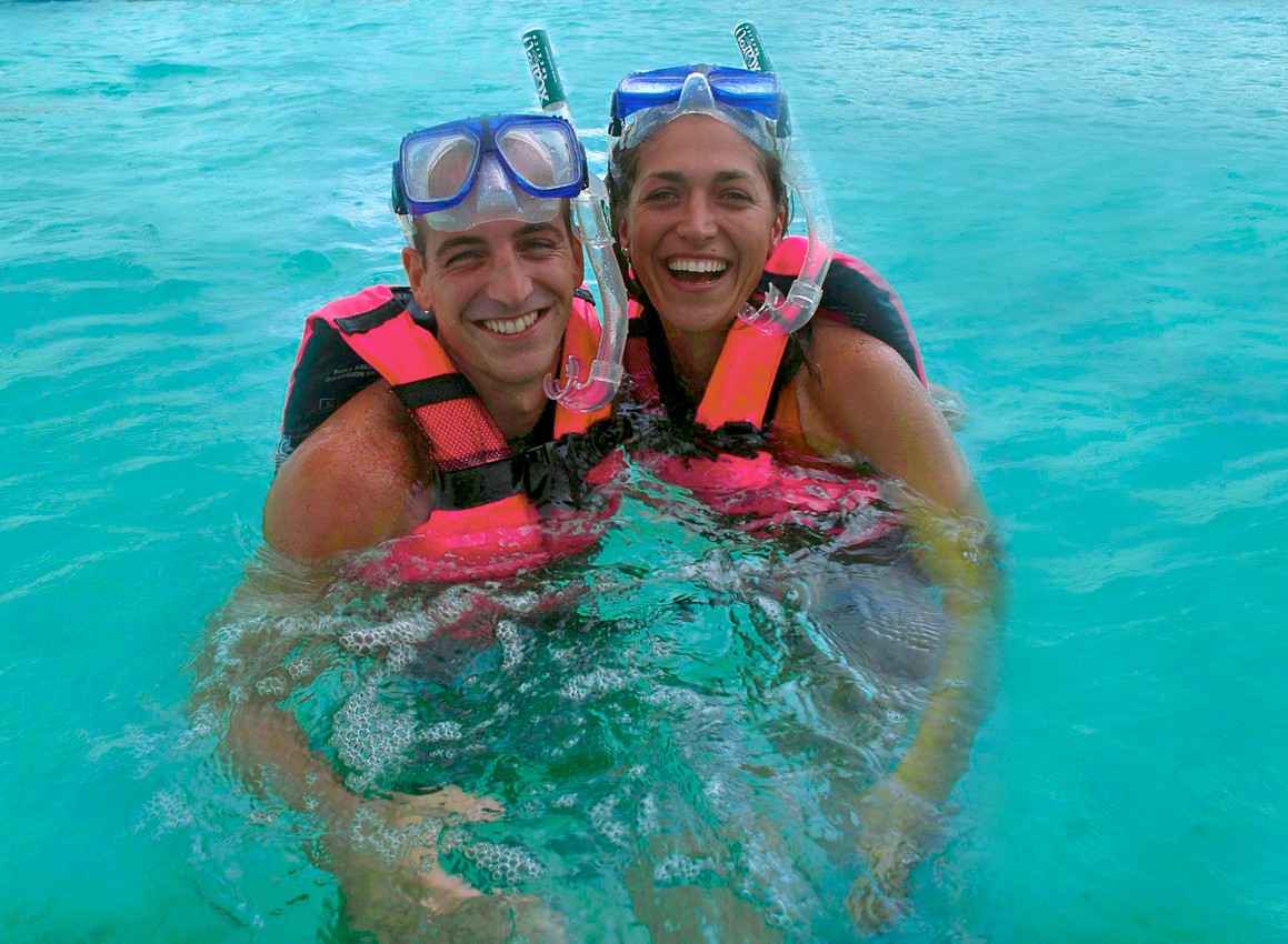 A man and a woman are smiling while they are snorkeling at Xcaret themepark.