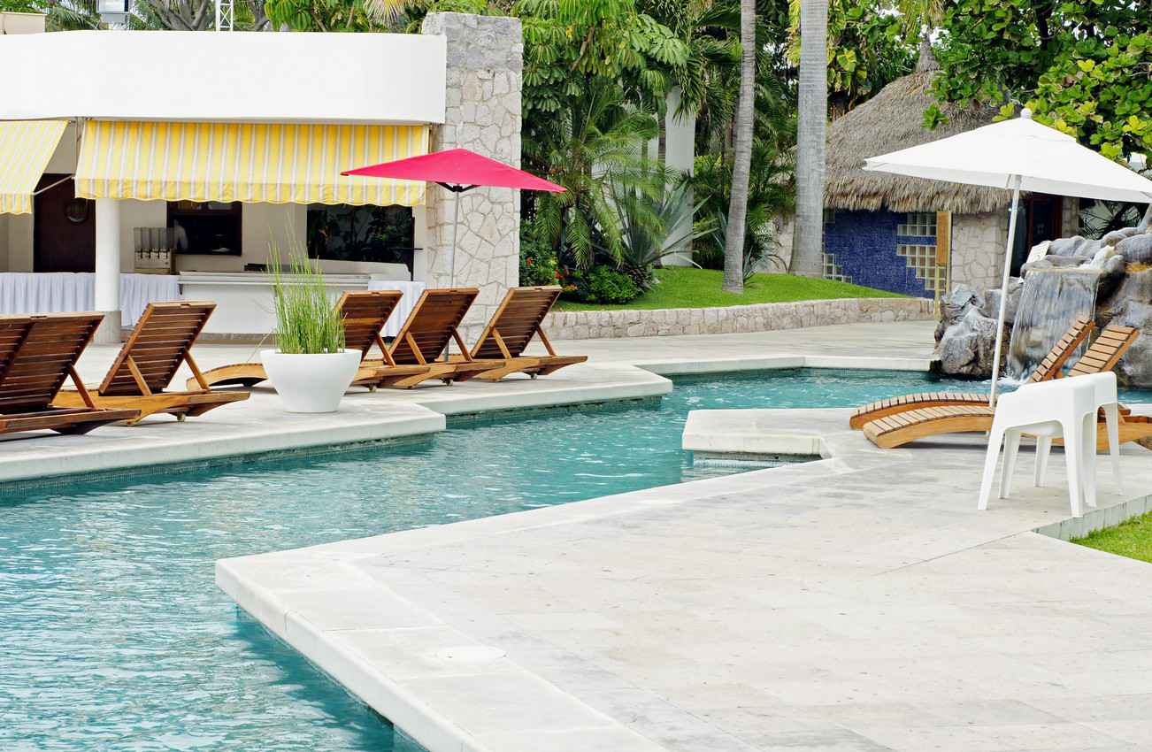 An example of a luxurious piece of property featuring a swimming pool with a waterfall and lounge chairs.