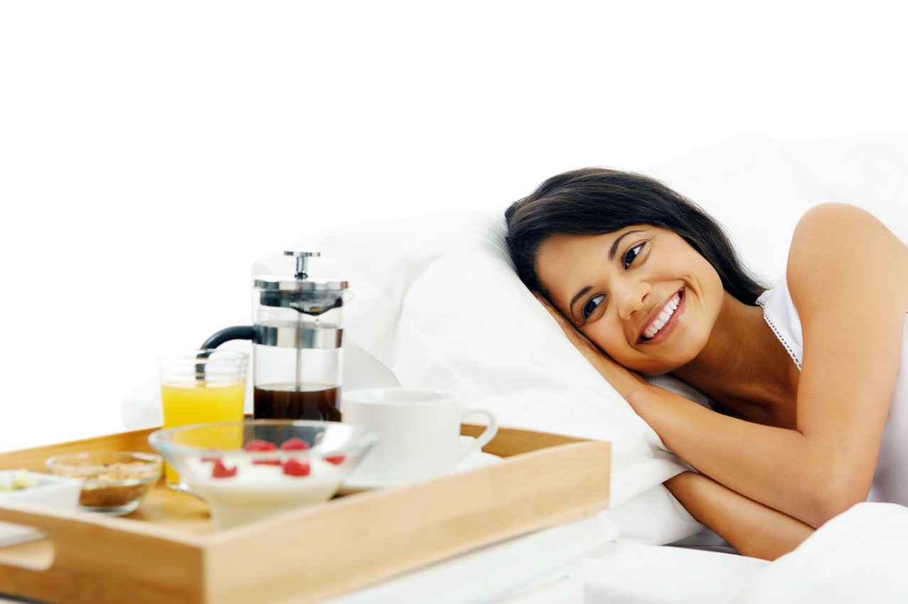A woman smiling after receding breakfast in bed as part of a wedding package in Playa Del Carmen.