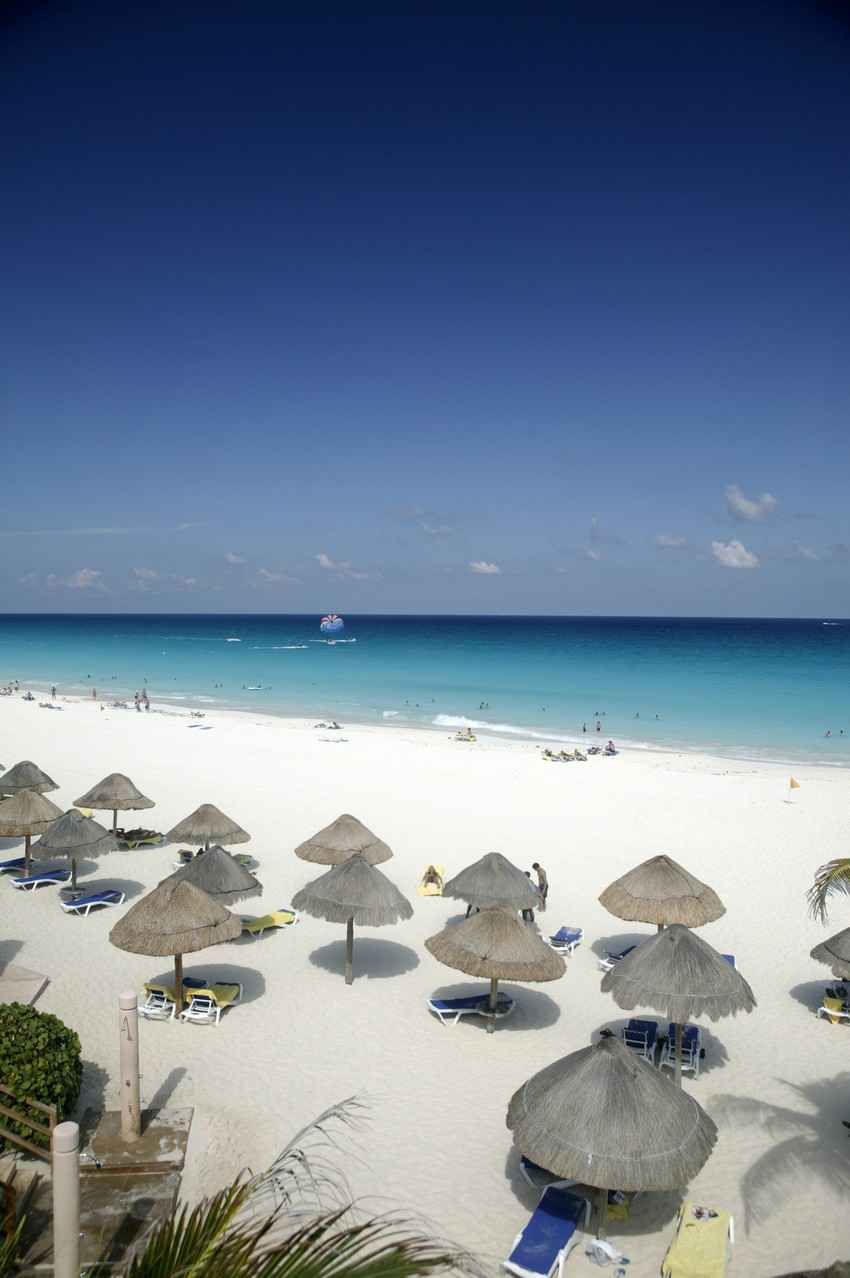 Several palapa beach umbrellas on a Caribbean beach.