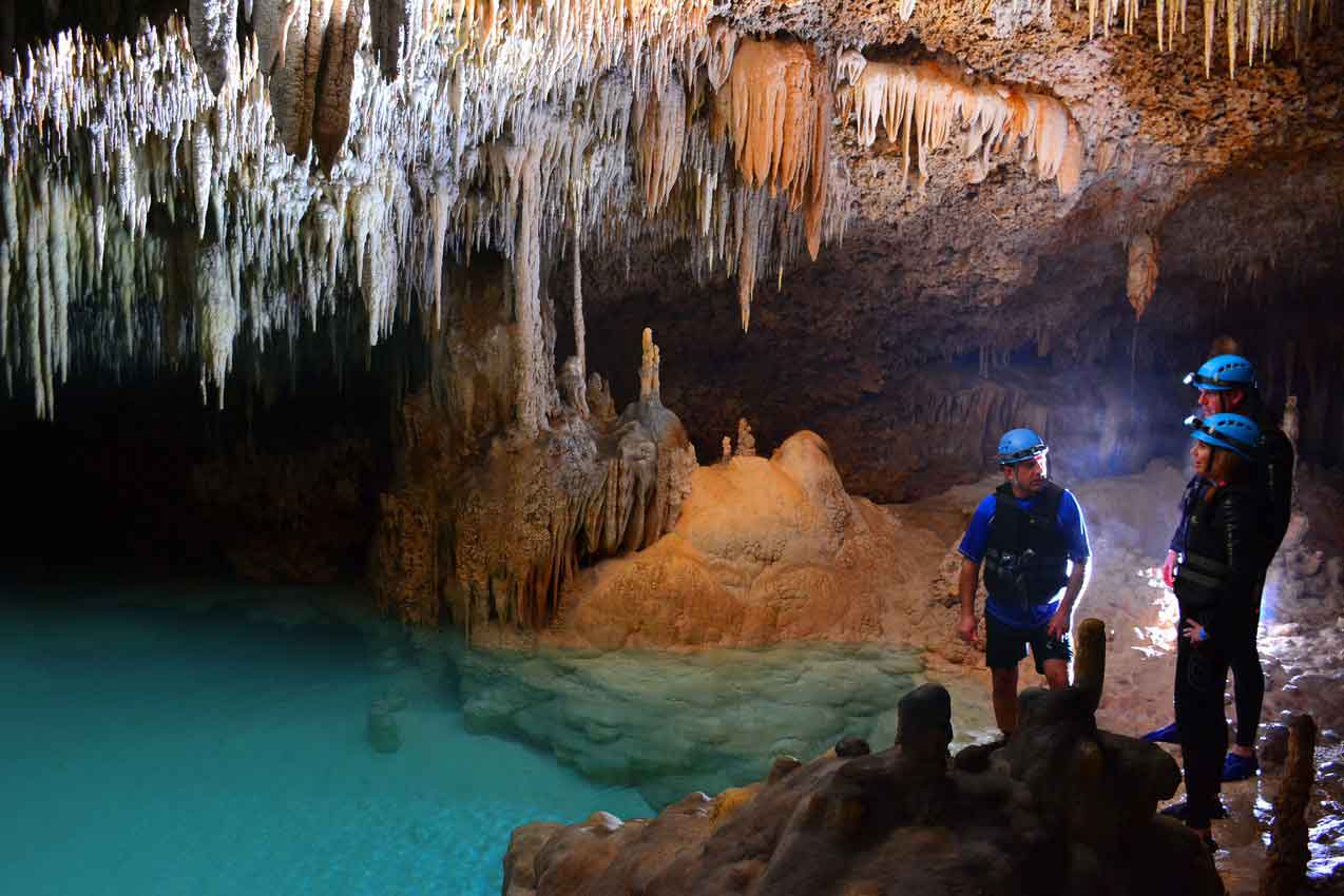 two-tourists-learning-about-ancient-stalagmites-and-stalactites-from-rio-secreto-mexico-guide