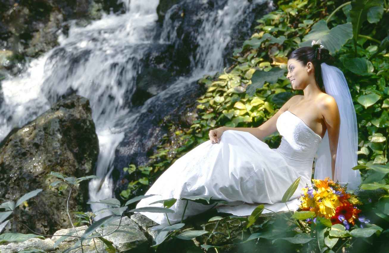 A bride sitting near a waterfall in the Riviera Mayan jungle.