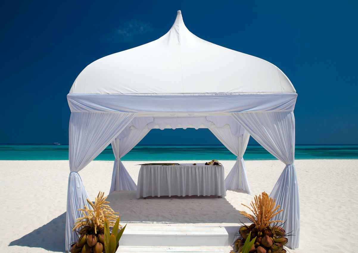 A wedding canopy on the Playa Del Carmen beach with calm water in the background.