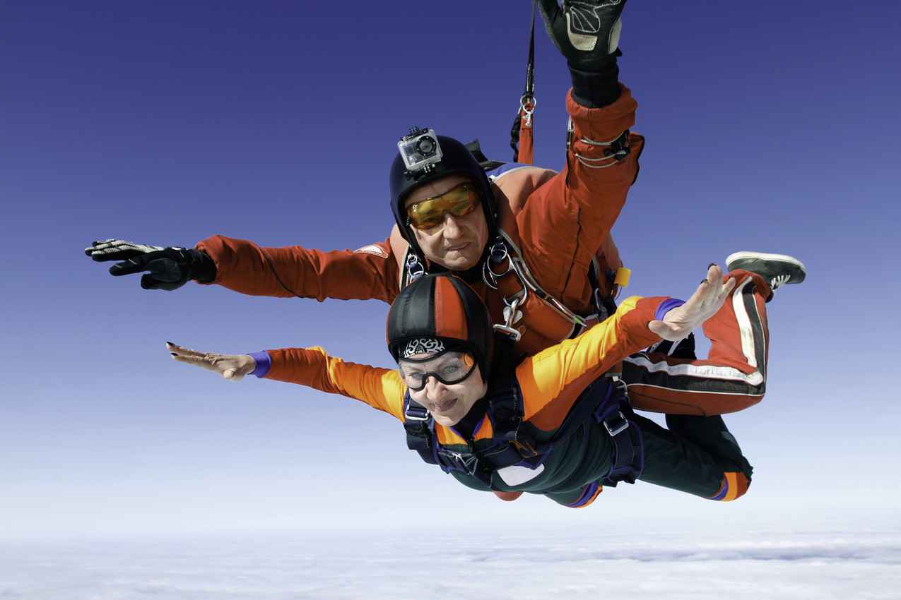 An older woman and a skydiving instructor doing a tandem jump together.