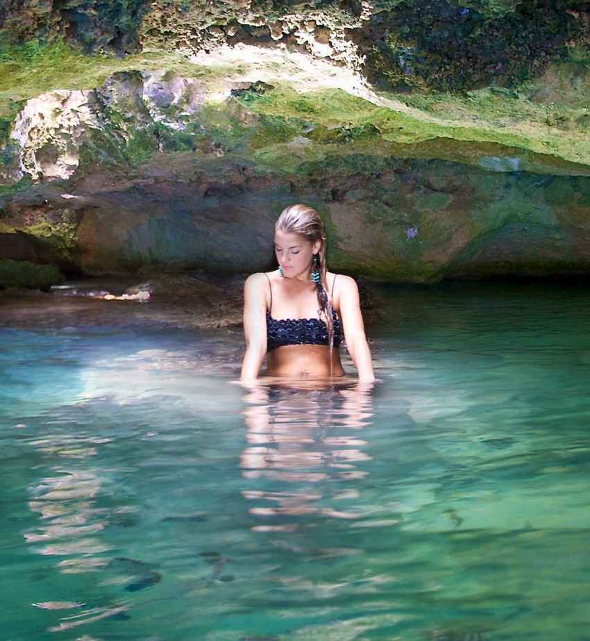 A beautiful woman taking a bath in a cenote.