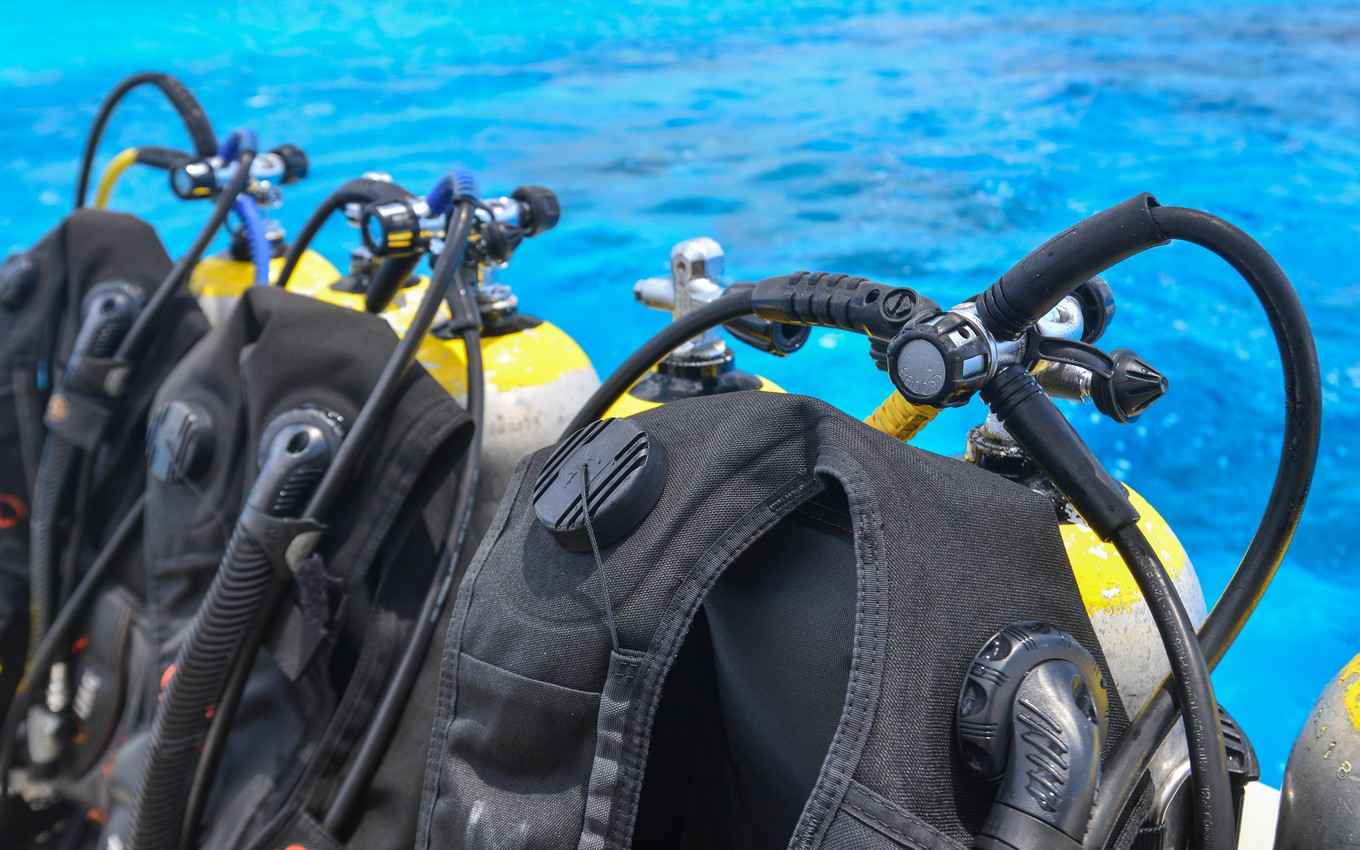 A long row of scuba diving tanks and equipment on a scuba diving boat.