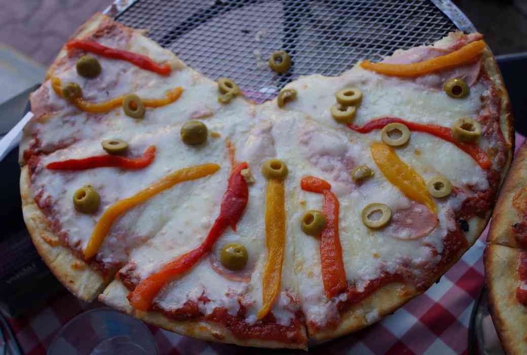 A ham, green olive, and pepper pizza at Lucky Luciano restaurant.