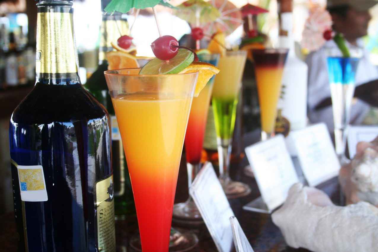 A number of various cocktails on a bar.