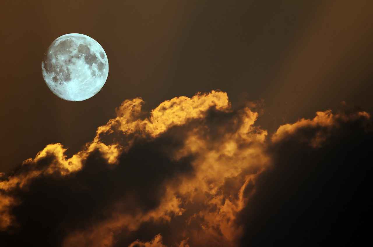 A bright and visible moon behind several clouds at night in Playa Del Carmen.