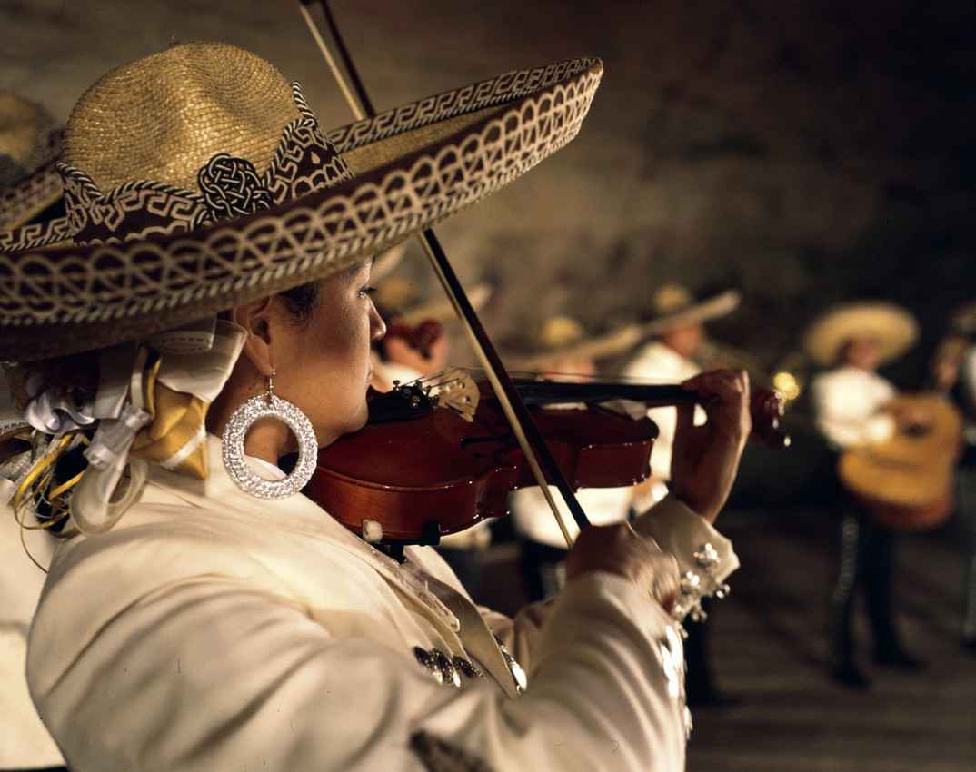 A Mexican woman wearing a sombrero and playing a violin.