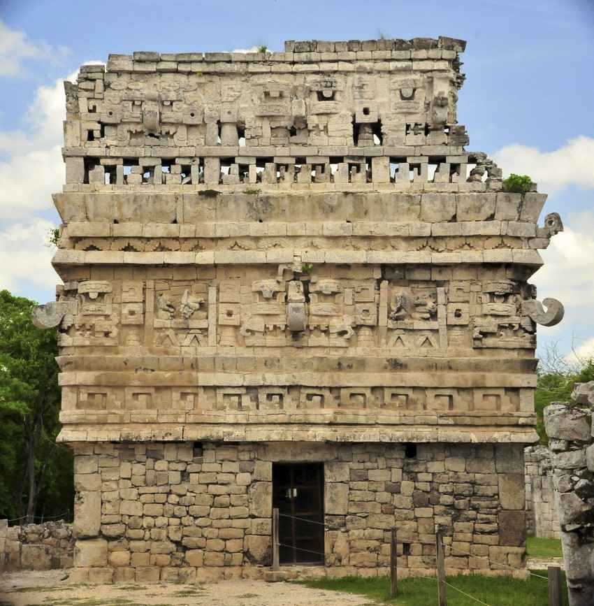 A large Mayan building in the center of ancient ruins.