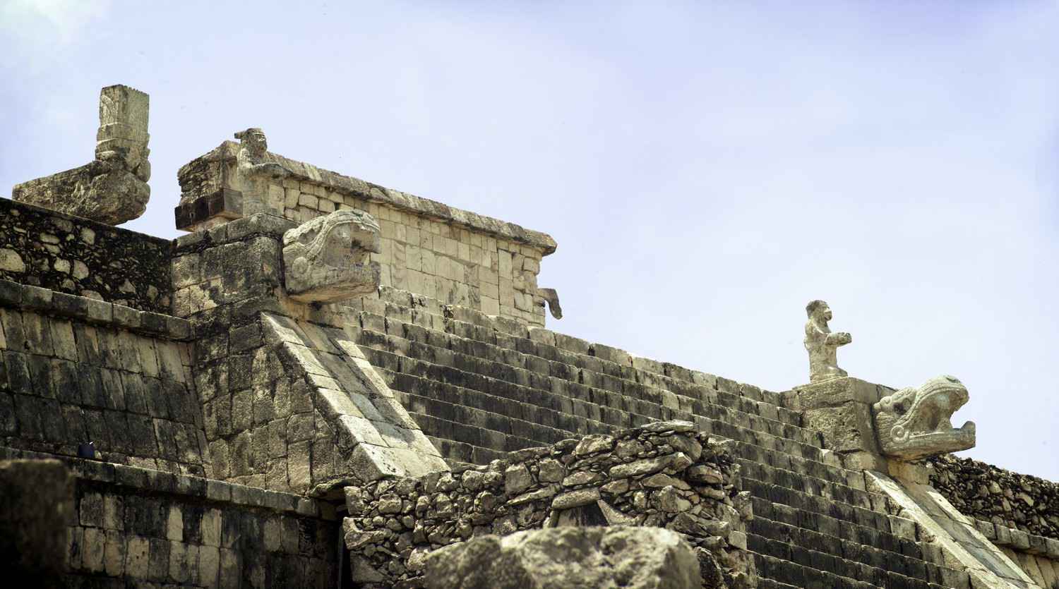 Statues of both a lizard and a snake on the side of a Mayan pyramid.