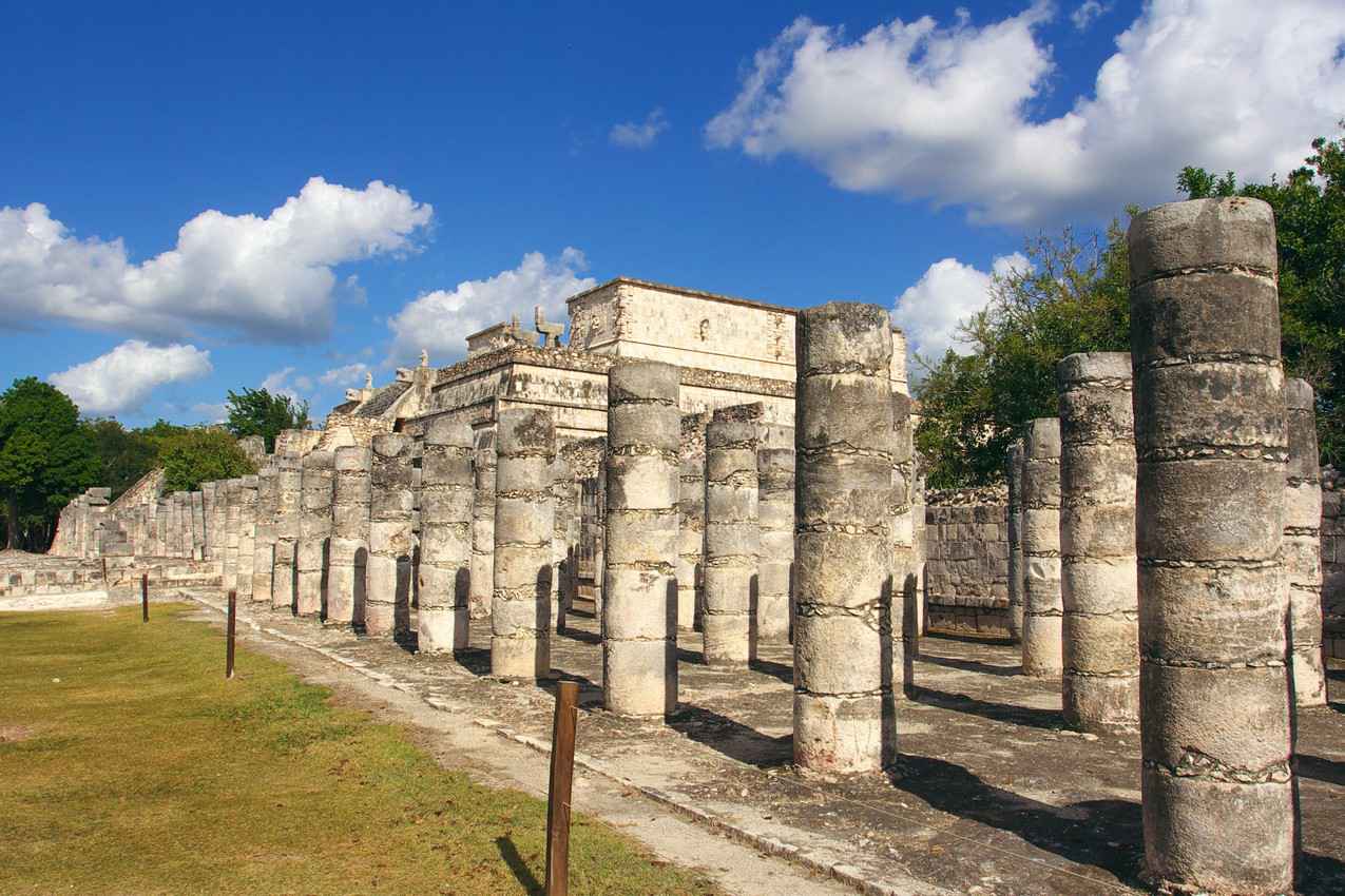 Several rows of columns in front of a building at Chichen Itza.