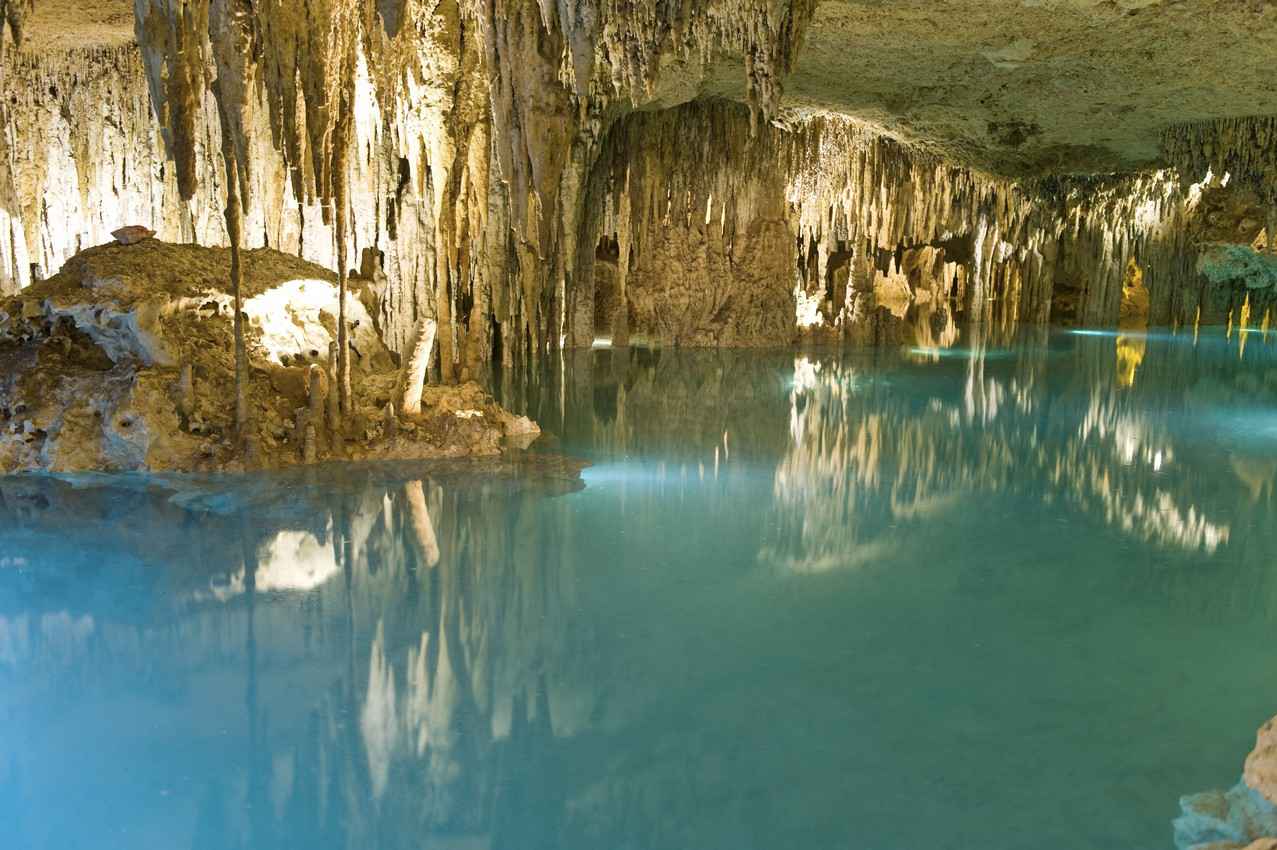 Several tourists swimming in a cenote cave.