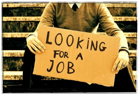 A man holding a sign that says "LOOKING FOR A JOB."