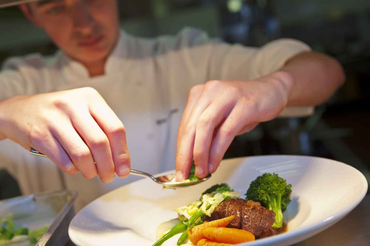 An experienced chef portioning a plate at one of the best all-inclusive resorts in Playa Del Carmen.