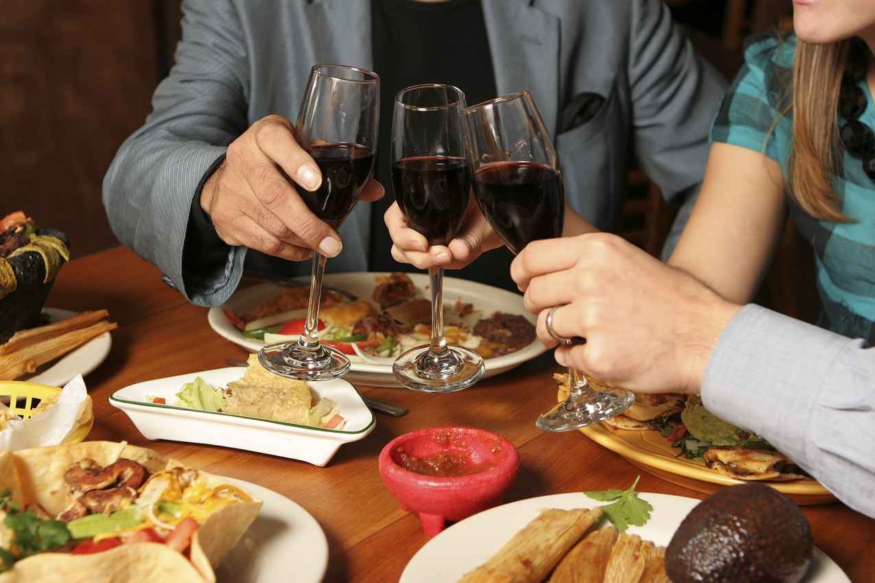 A family of three drinking wine with a traditional Mexican dinner.
