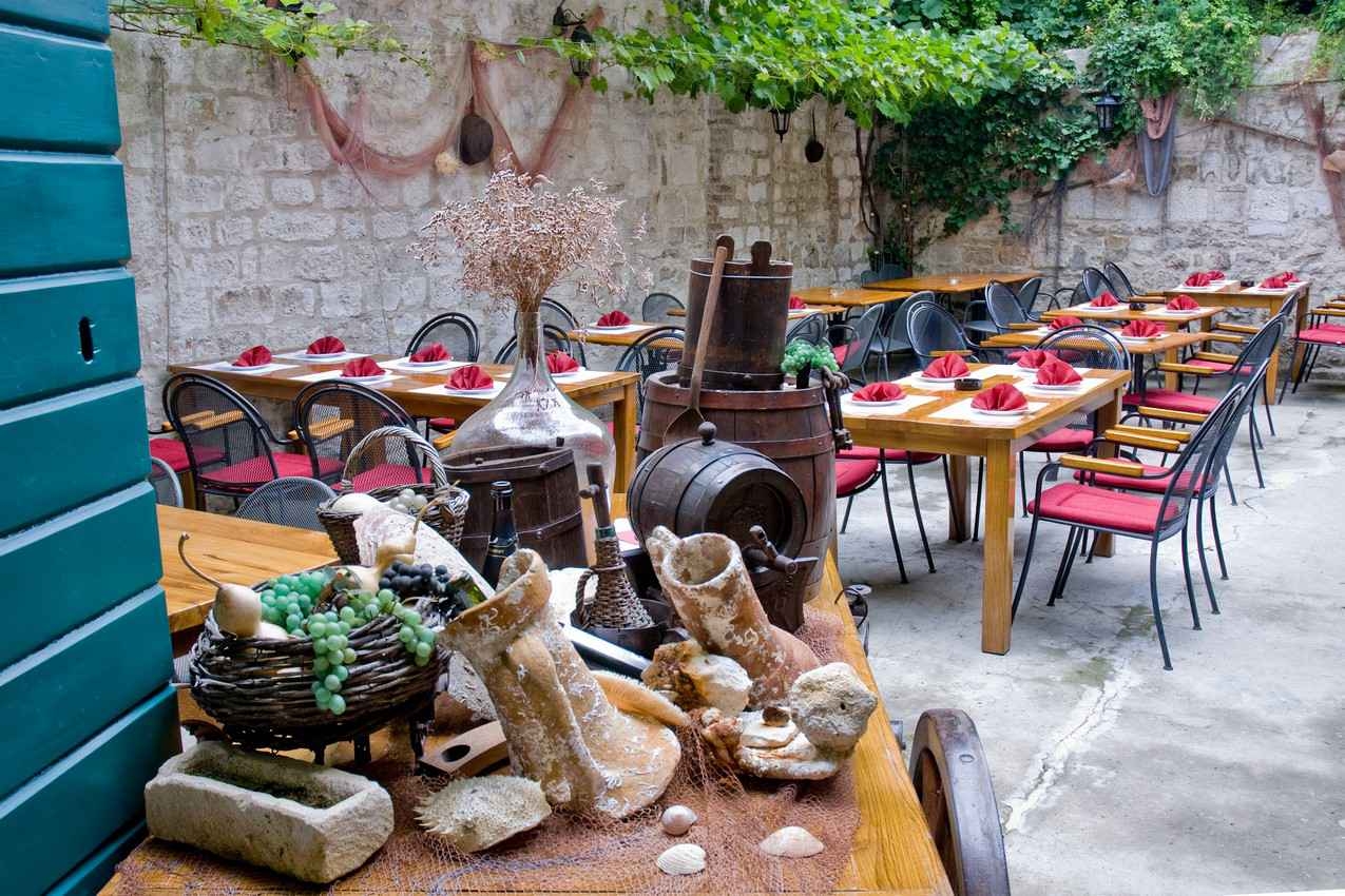 An outdoor restaurant with lots of seating and plants surrounding the dining area.