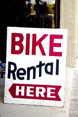 A wooden bike rental here sign.