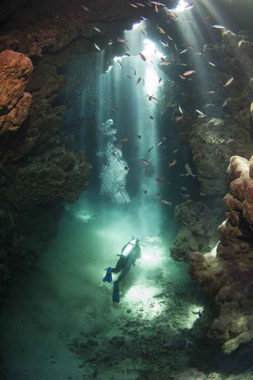 Several scuba divers deep inside an underground cenote.