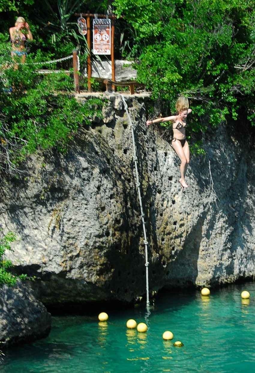 Several people jumping from the "Cliff of Courage" above a local cenote.