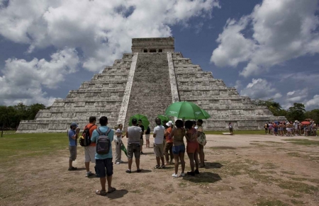 Another group of tourists standing in front of the large pyramid El Castillo.