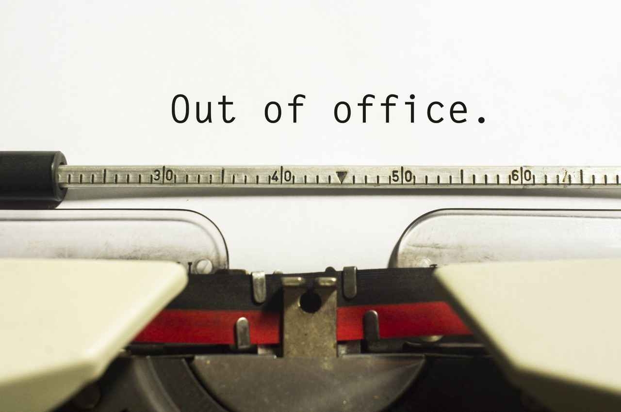 A piece of paper in a typewriter with, out of office, written on it.