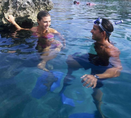 A man and a woman who are celebrating their honeymoon snorkeling together.