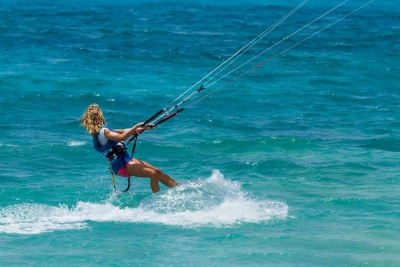 A very strong woman kite boarding in rough waters.