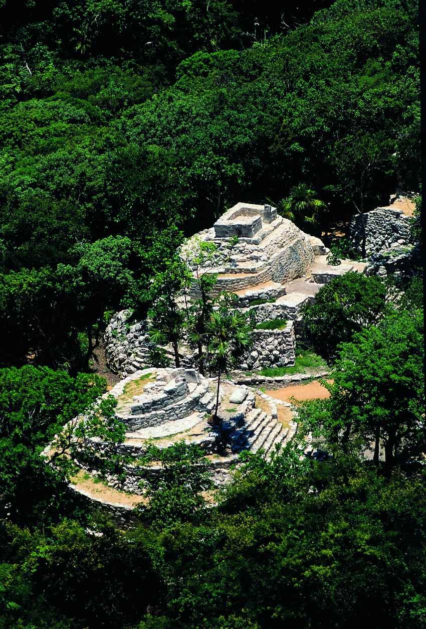 An aerial view of several Mayan pyramids in the middle of the jungle.