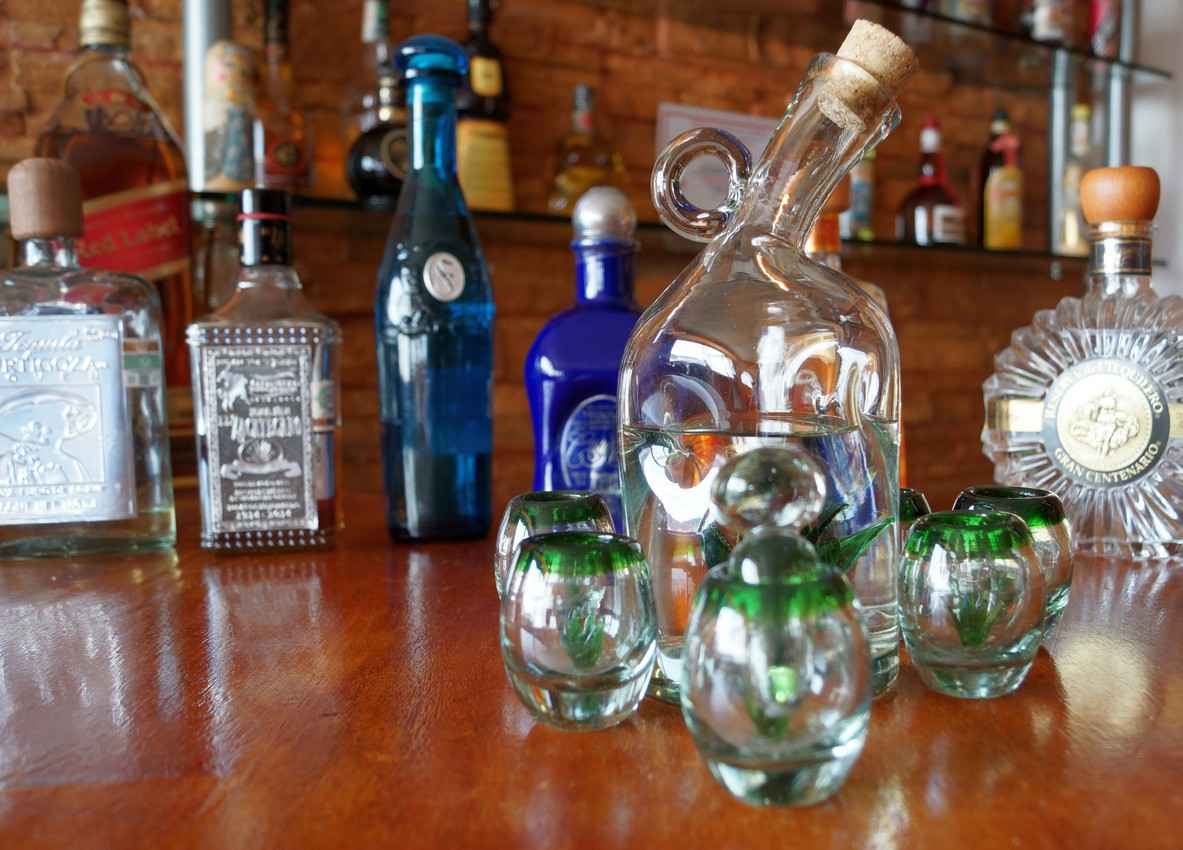 A group of several different beautiful tequila bottles lined up on a bar.