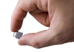 A man holding a micro SD card between his fingers.