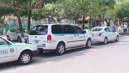 Several taxis lined up on a Playa Del Carmen street.