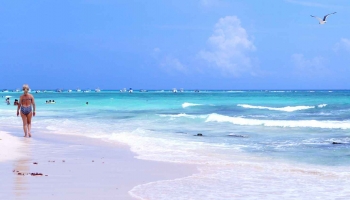A beautiful beach in Playa Del Carmen with white sand and baby blue water.