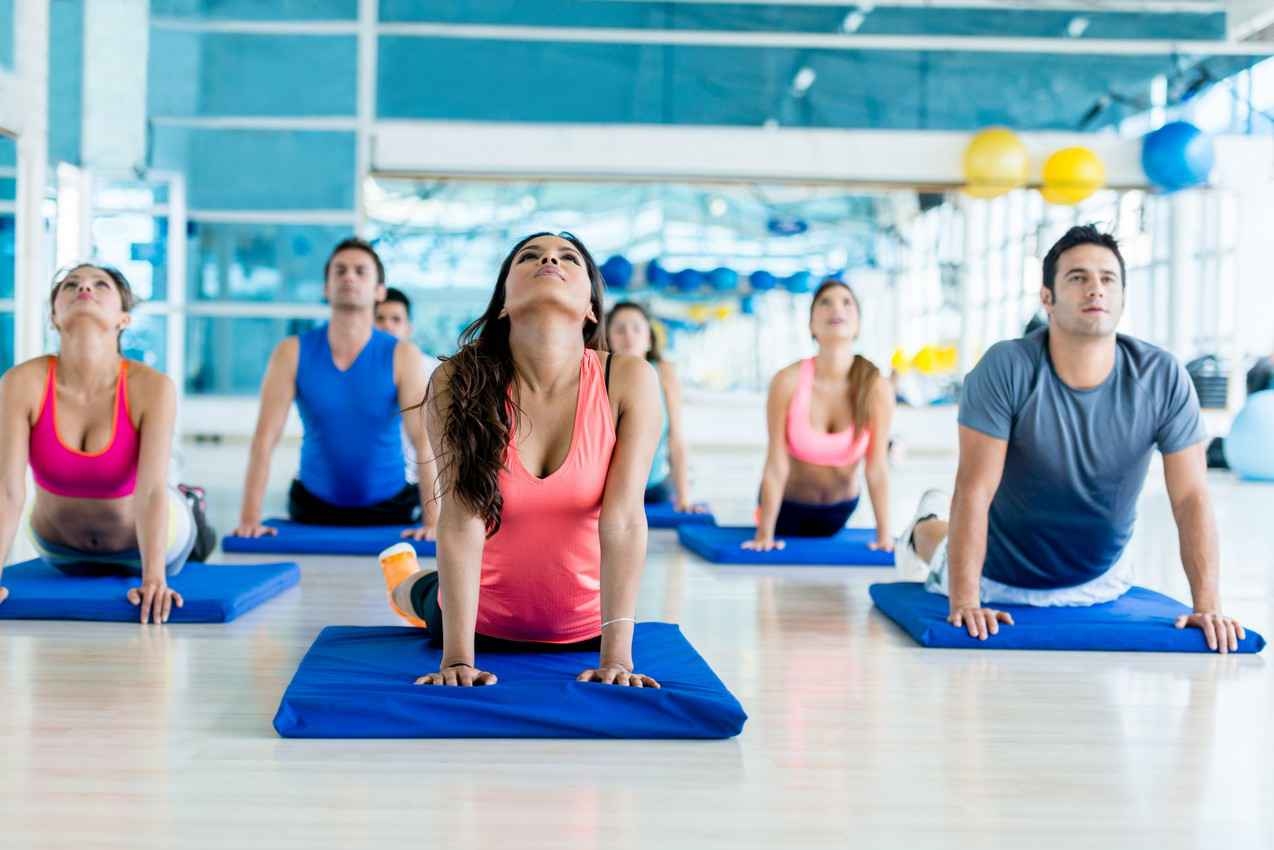 A mixed group of men and women doing yoga at a gym.
