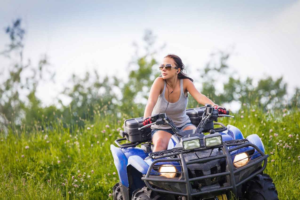 A woman riding an ATV and listening to music at the same time.