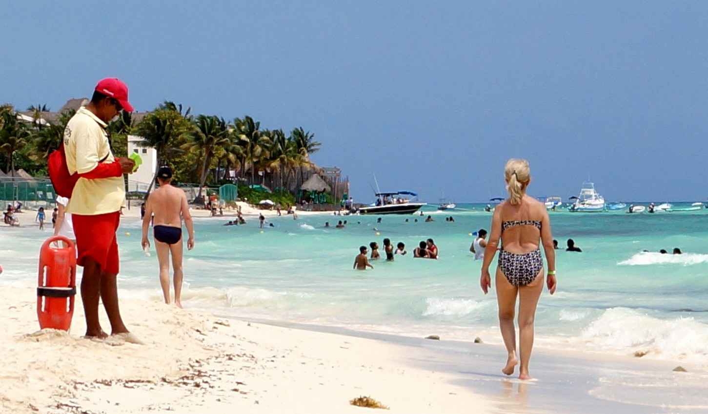 A middle-aged woman walked down the beach near a lifeguard in Playa Del Carmen.